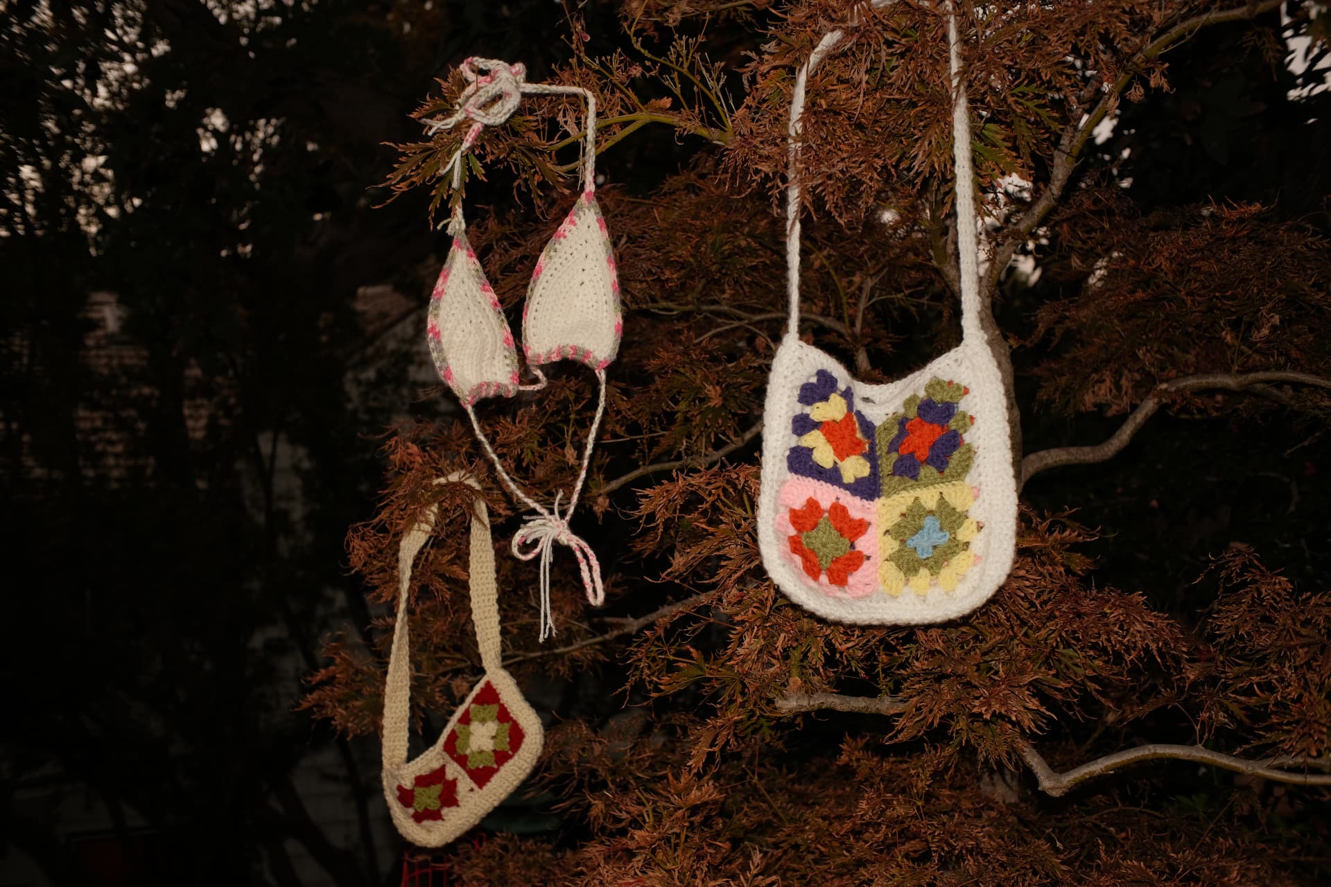 Ivory crochet tops and colorful floral bags hanging among tree branches